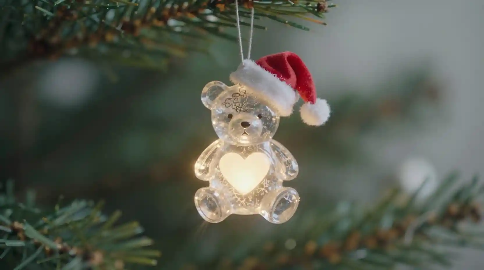 Decorazione natalizia di orsacchiotto che brilla su un ramo festivo