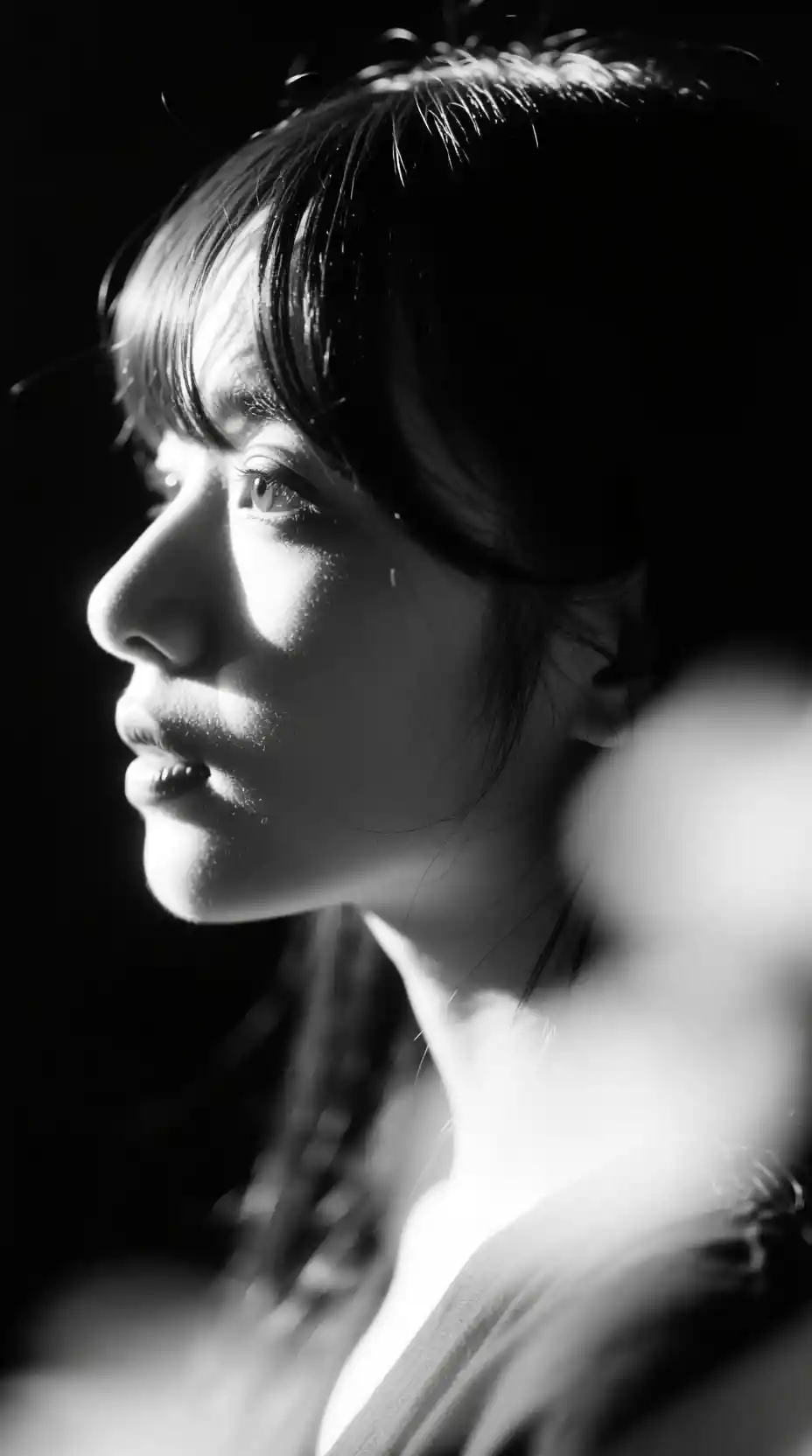 Backlit black and white close up portrait of a young woman