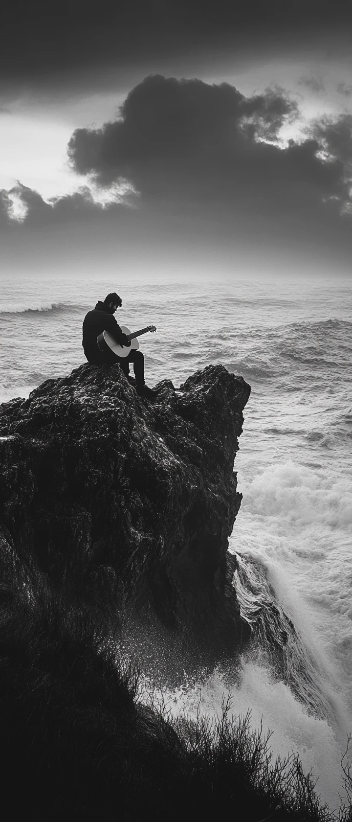 Solitary man playing guitar on rocks by stormy sea