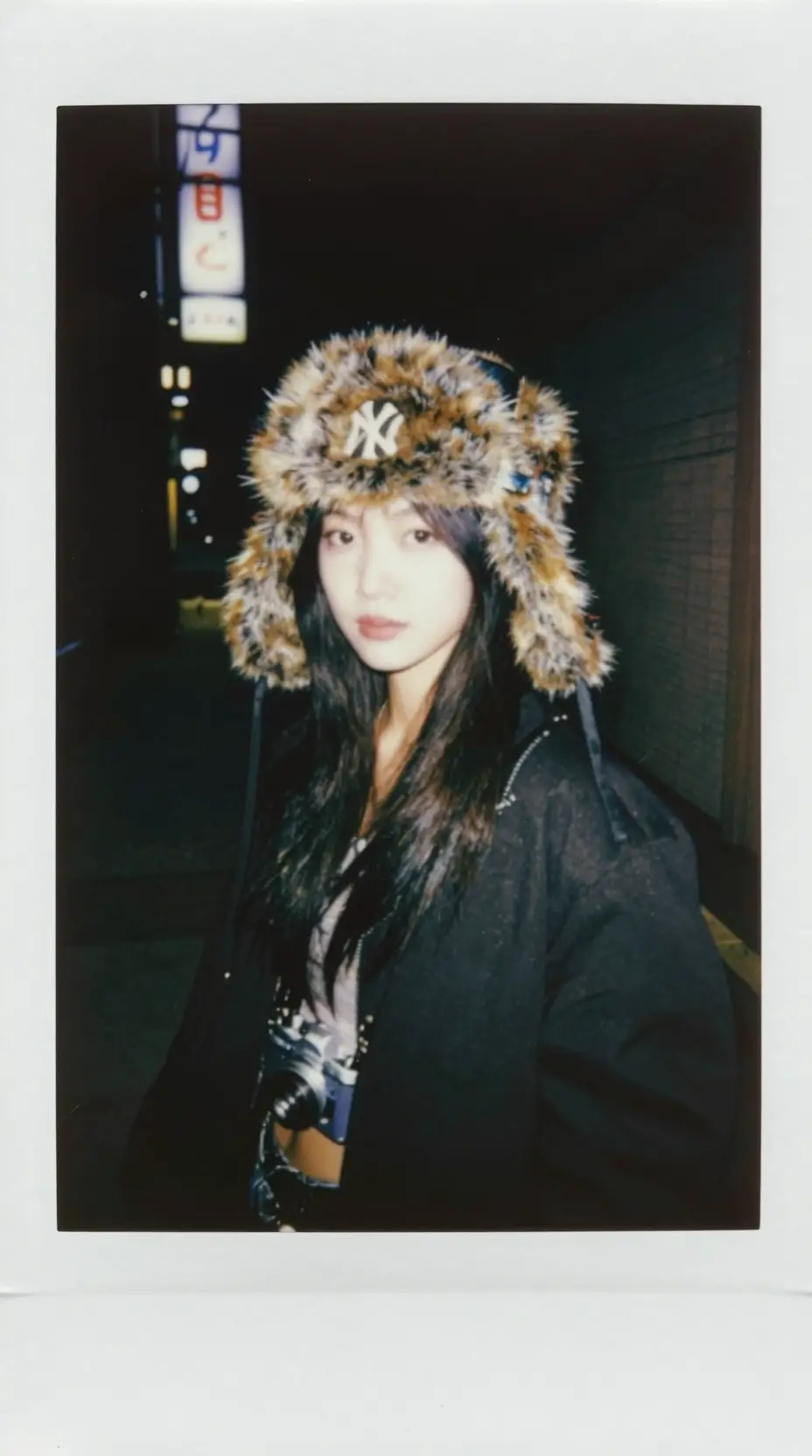 A young woman wearing a leopard print ushanka hat and a camera at night