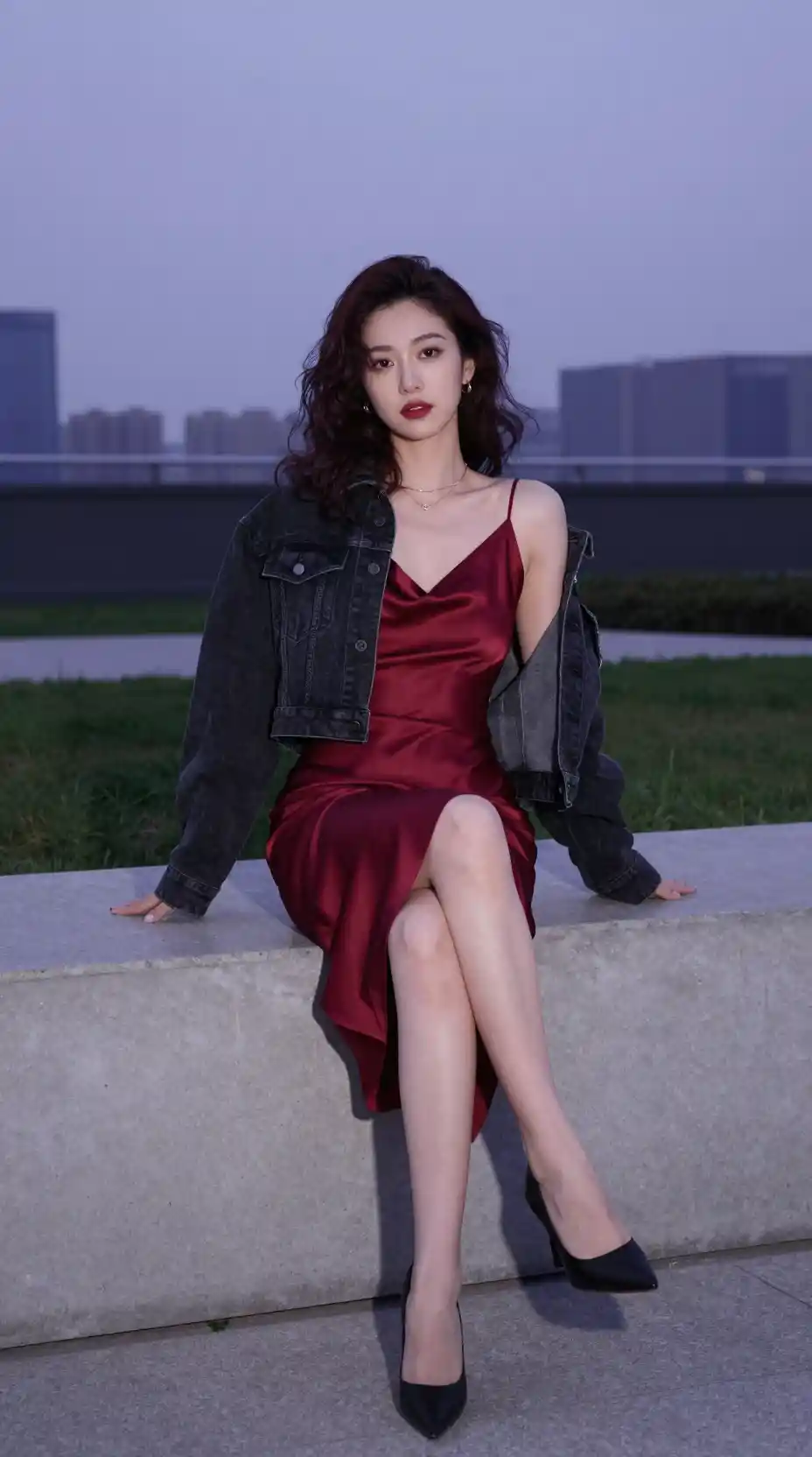 Woman in red slip dress sitting over an urban park