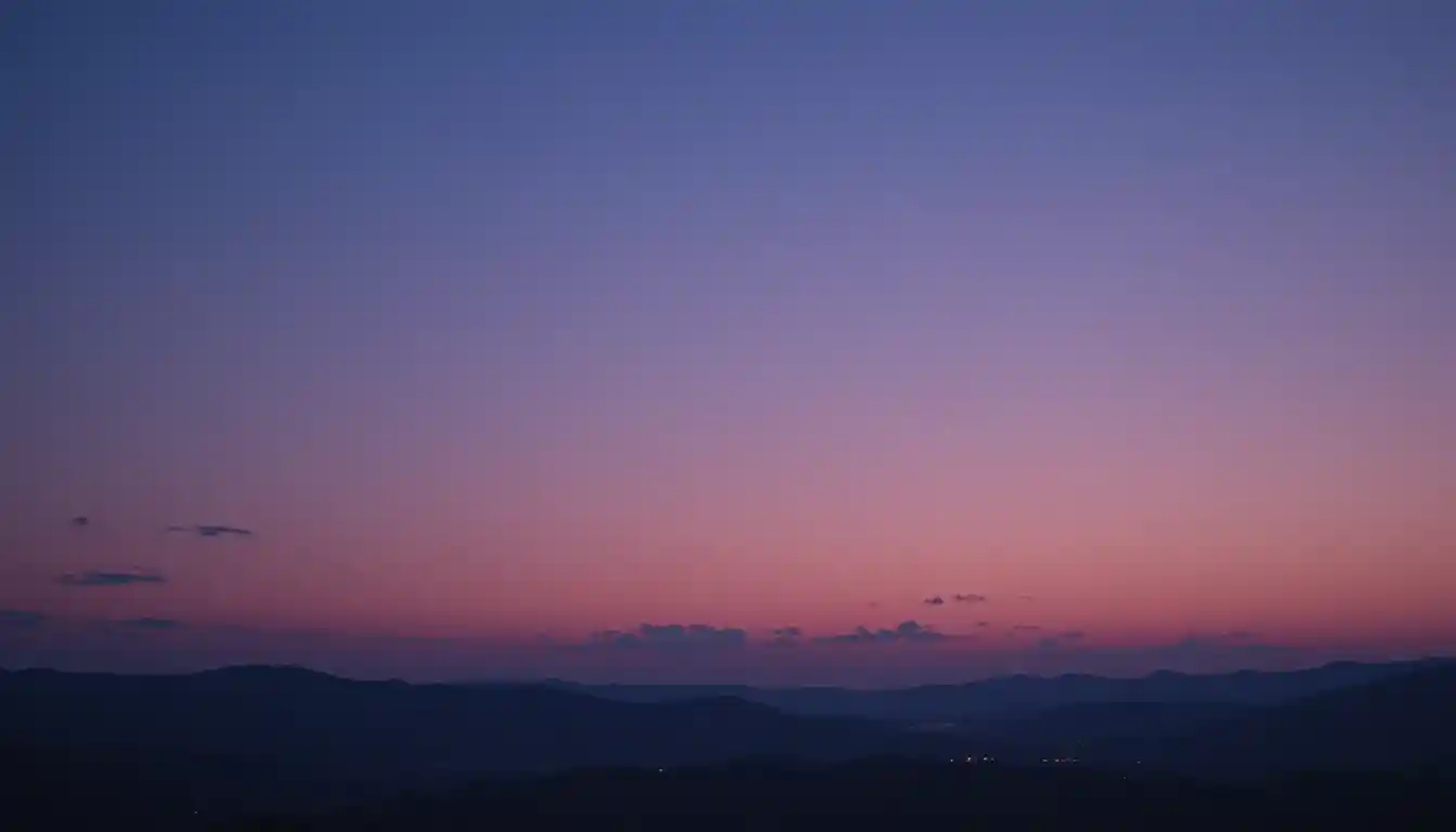 Wide twilight sky with mountains and soft scattered clouds