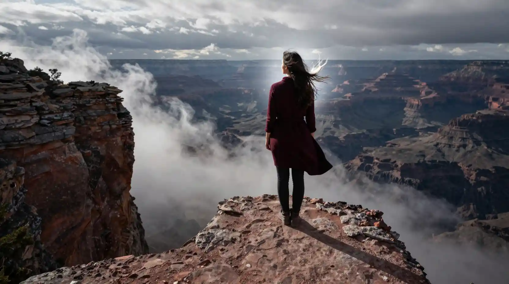 Donna sul bordo di una scogliera sopra un canyon di nuvole turbinanti