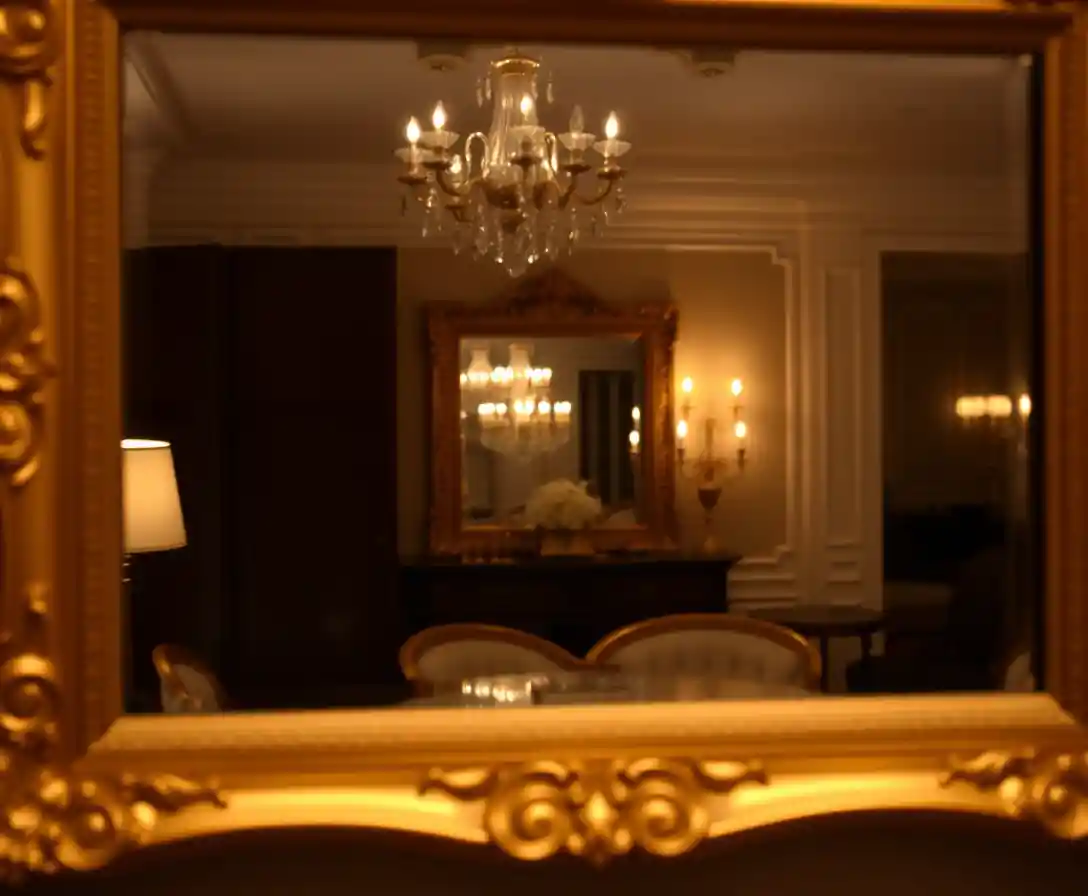 Miroir à cadre doré reflétant une pièce élégante à la lumière douce
