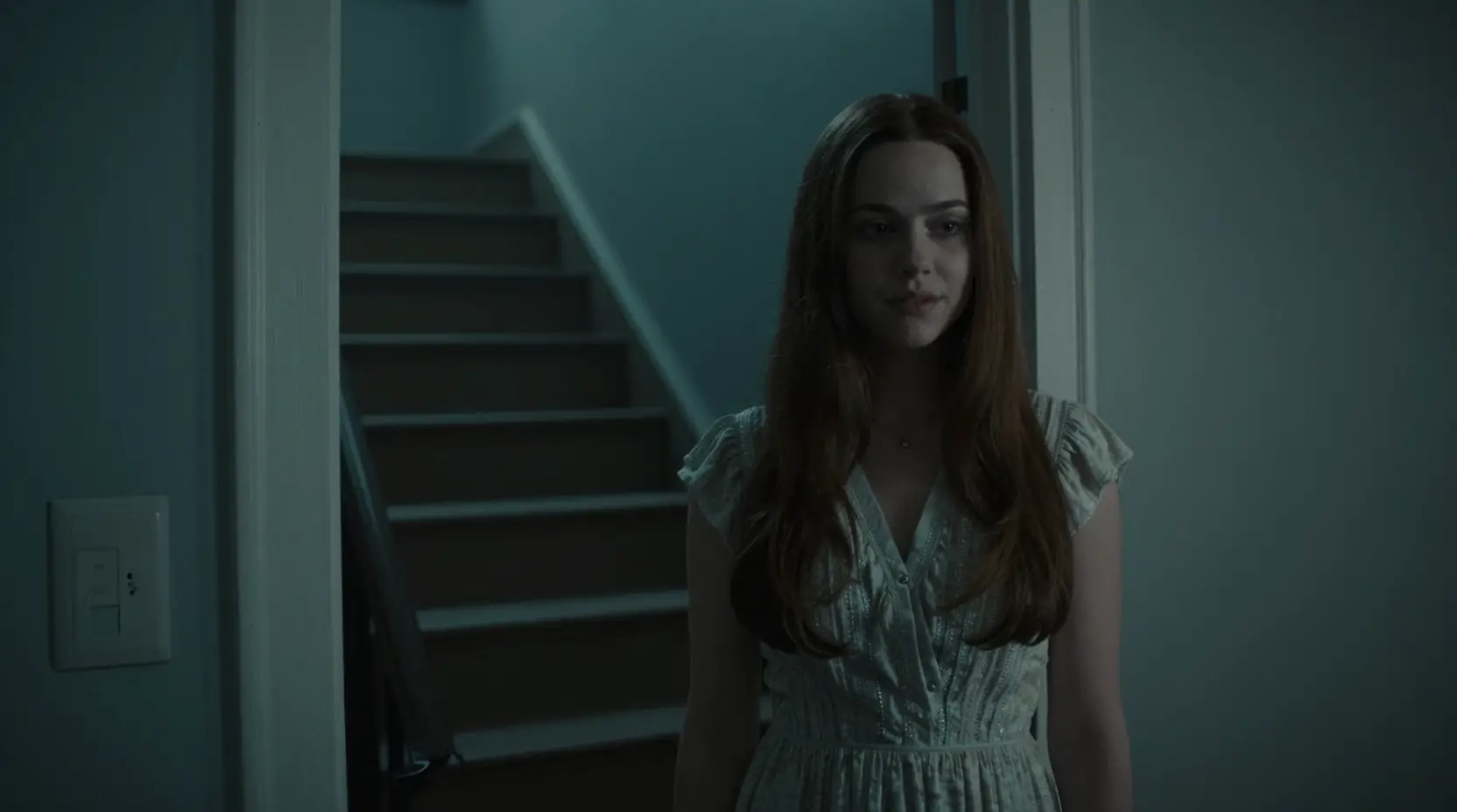 Sweet neighbor woman standing by a dim stairwell door