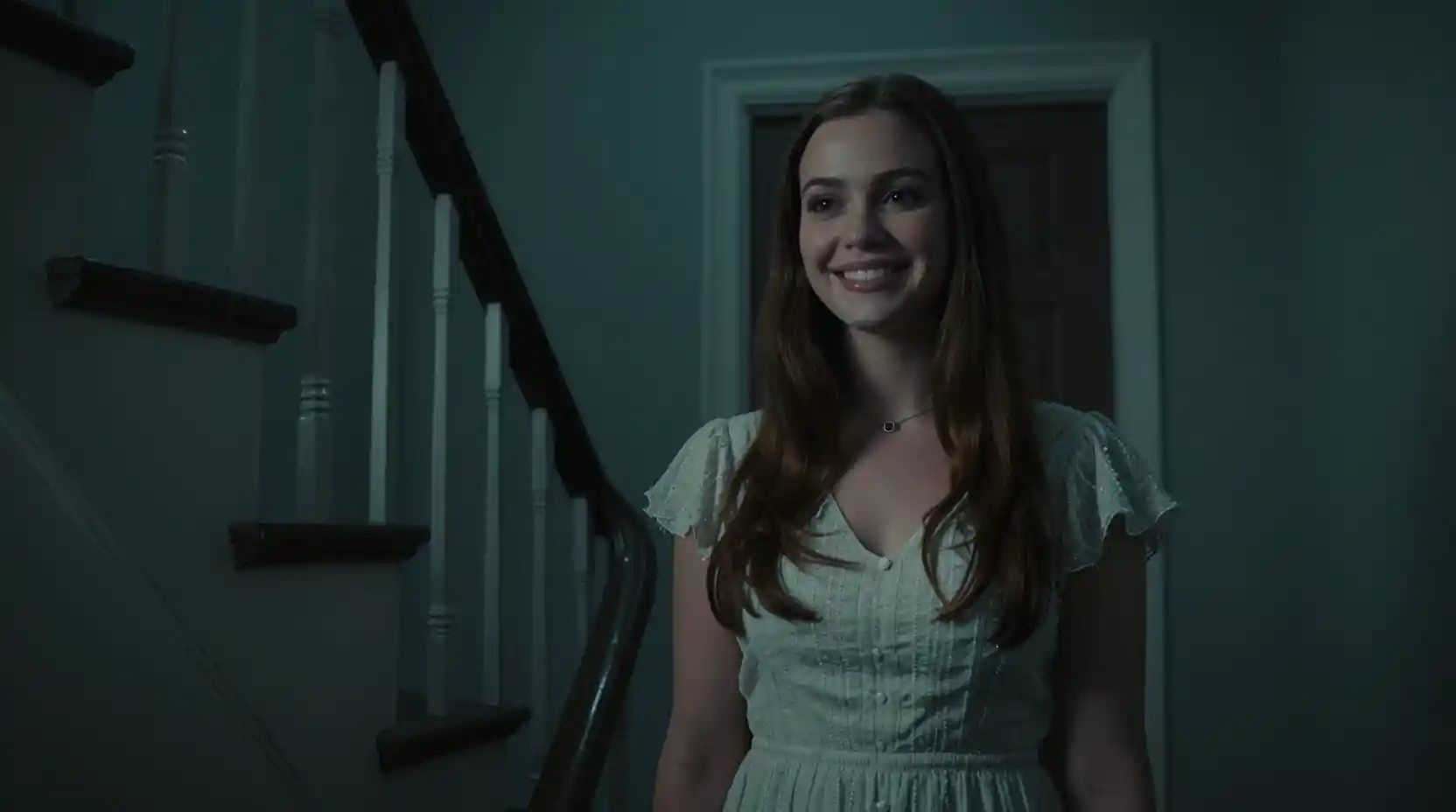 Woman at her front door in a dark cinematic stairwell