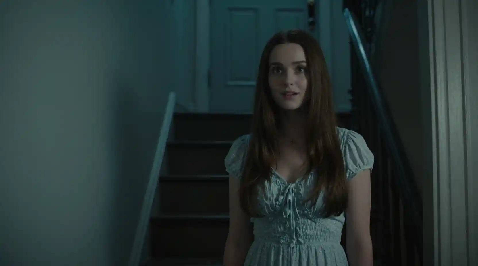 Woman by her front door in a dark stairwell
