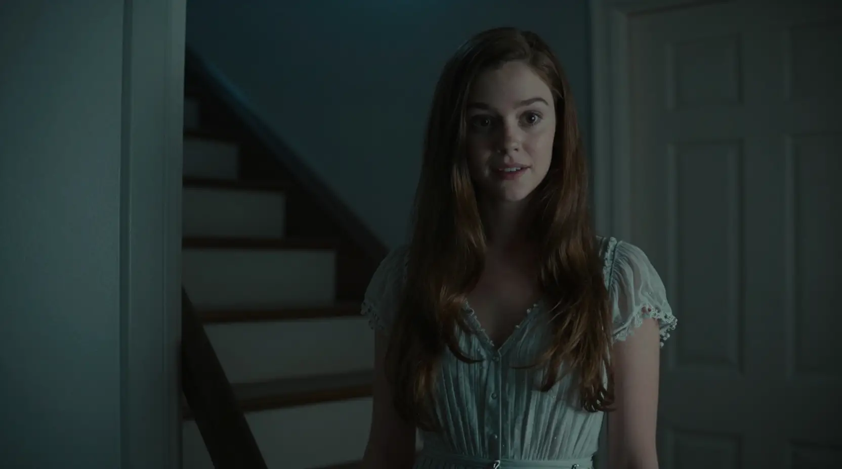 Woman by her front door in a dark cinematic stairwell