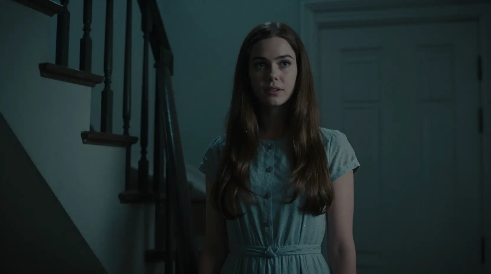 Woman at her front door in a dark stairwell