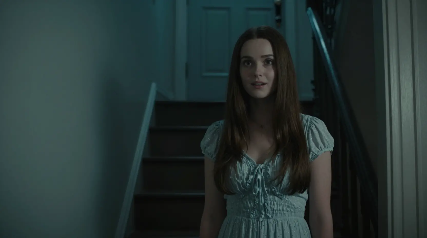 Woman by her front door in a dark stairwell
