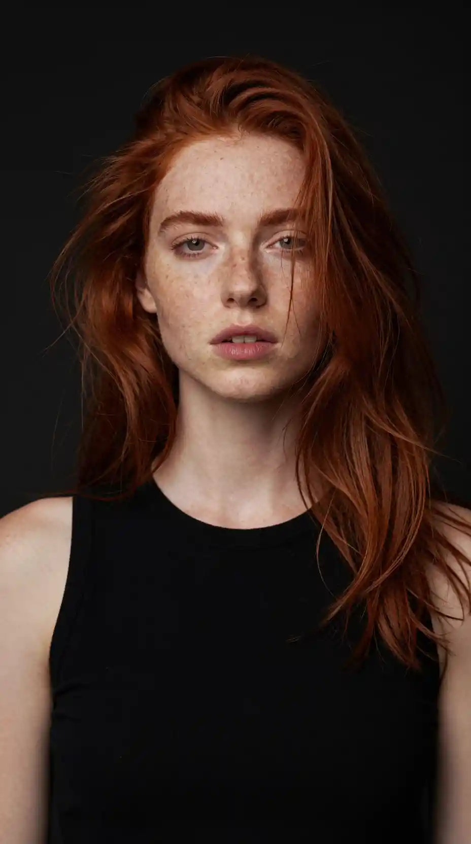 Red haired woman portrait with freckles against dark background