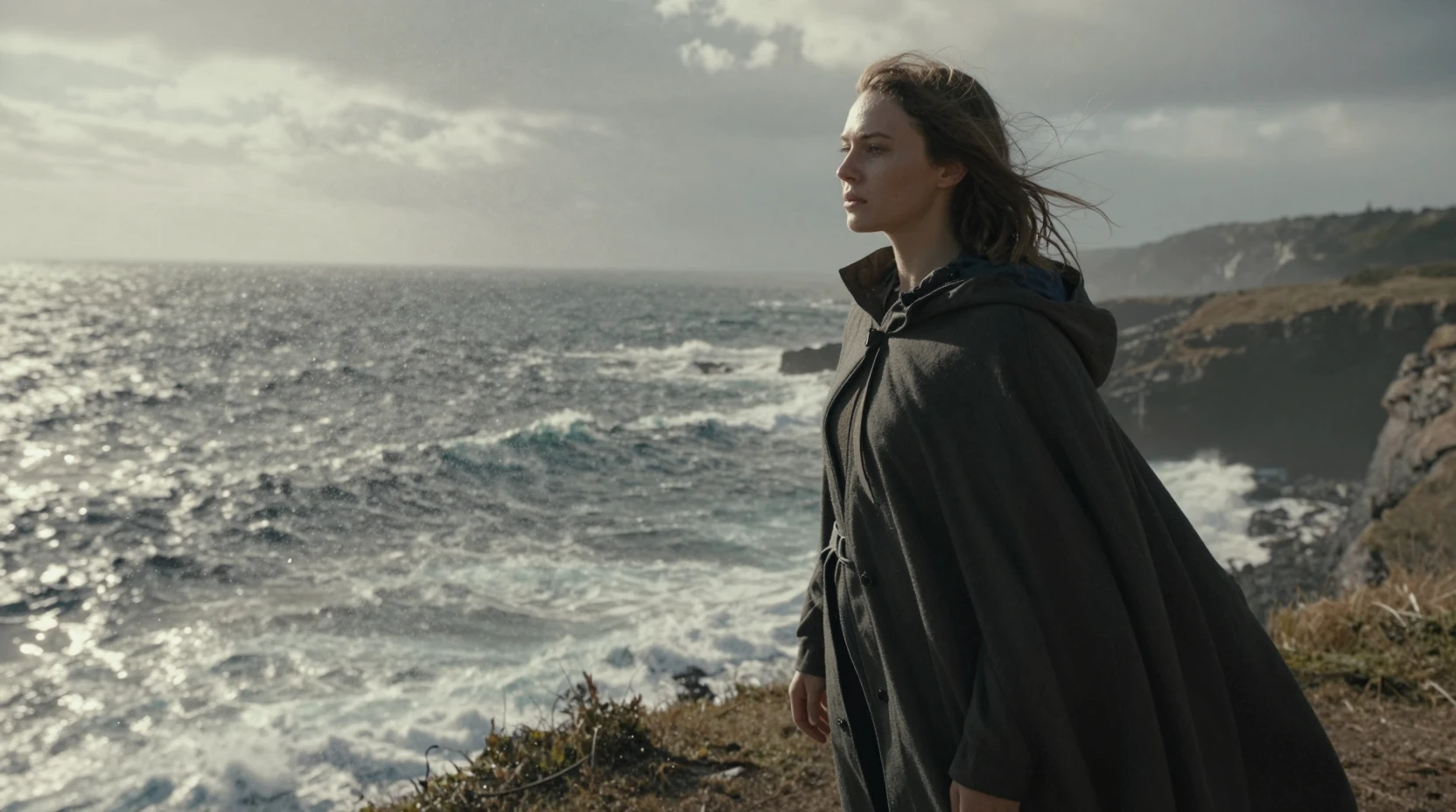 Young woman on a windswept sea cliff in harsh sunlight