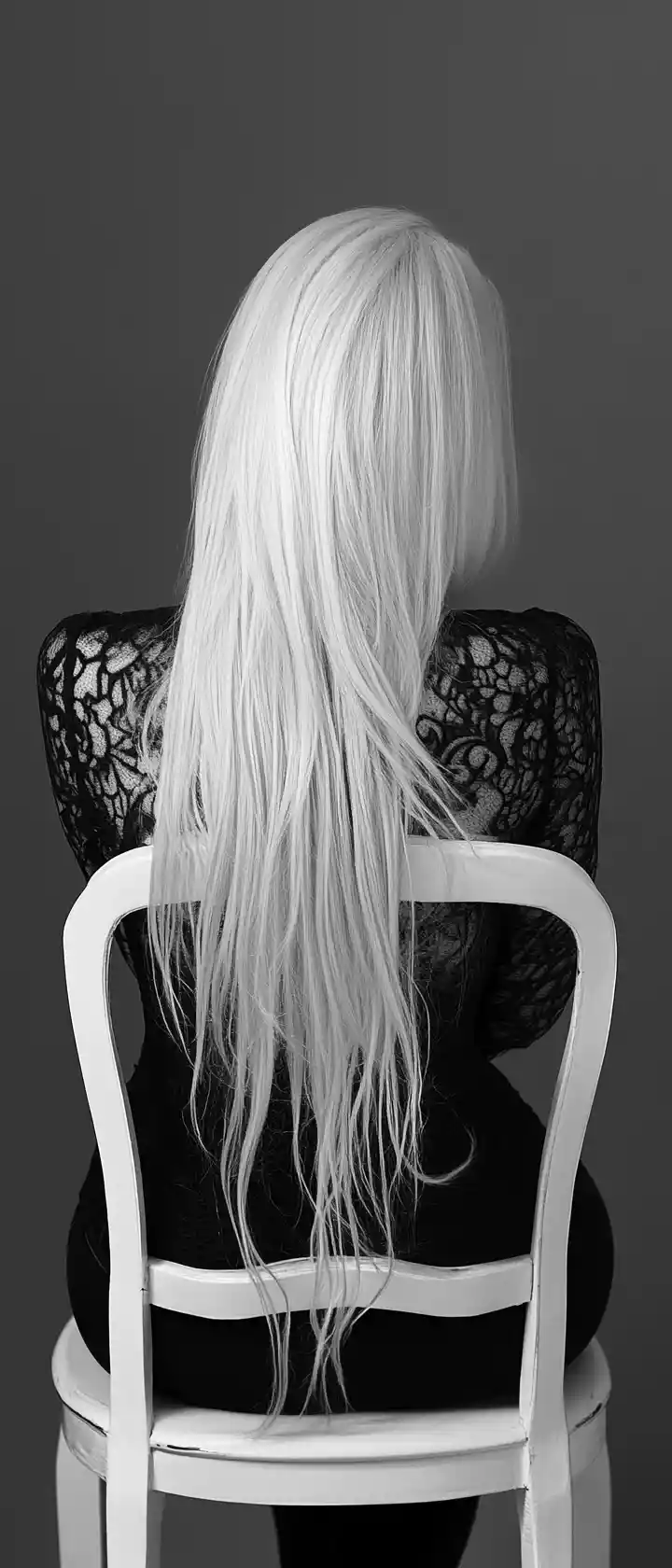 Woman leaning forward on a white chair in monochrome