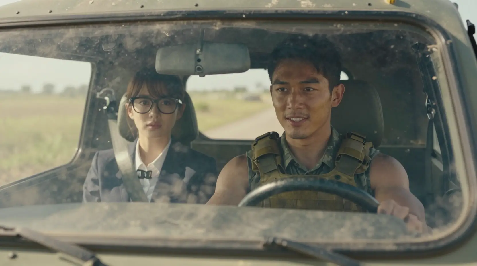 Soldier driving armored vehicle across sunlit dusty grassland