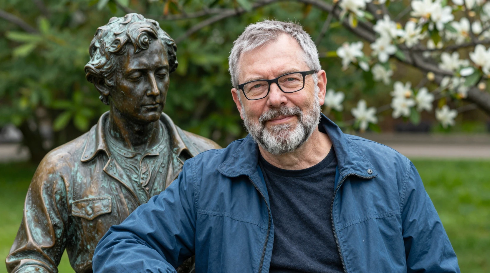 Middle aged man smiling beside bronze statue in garden