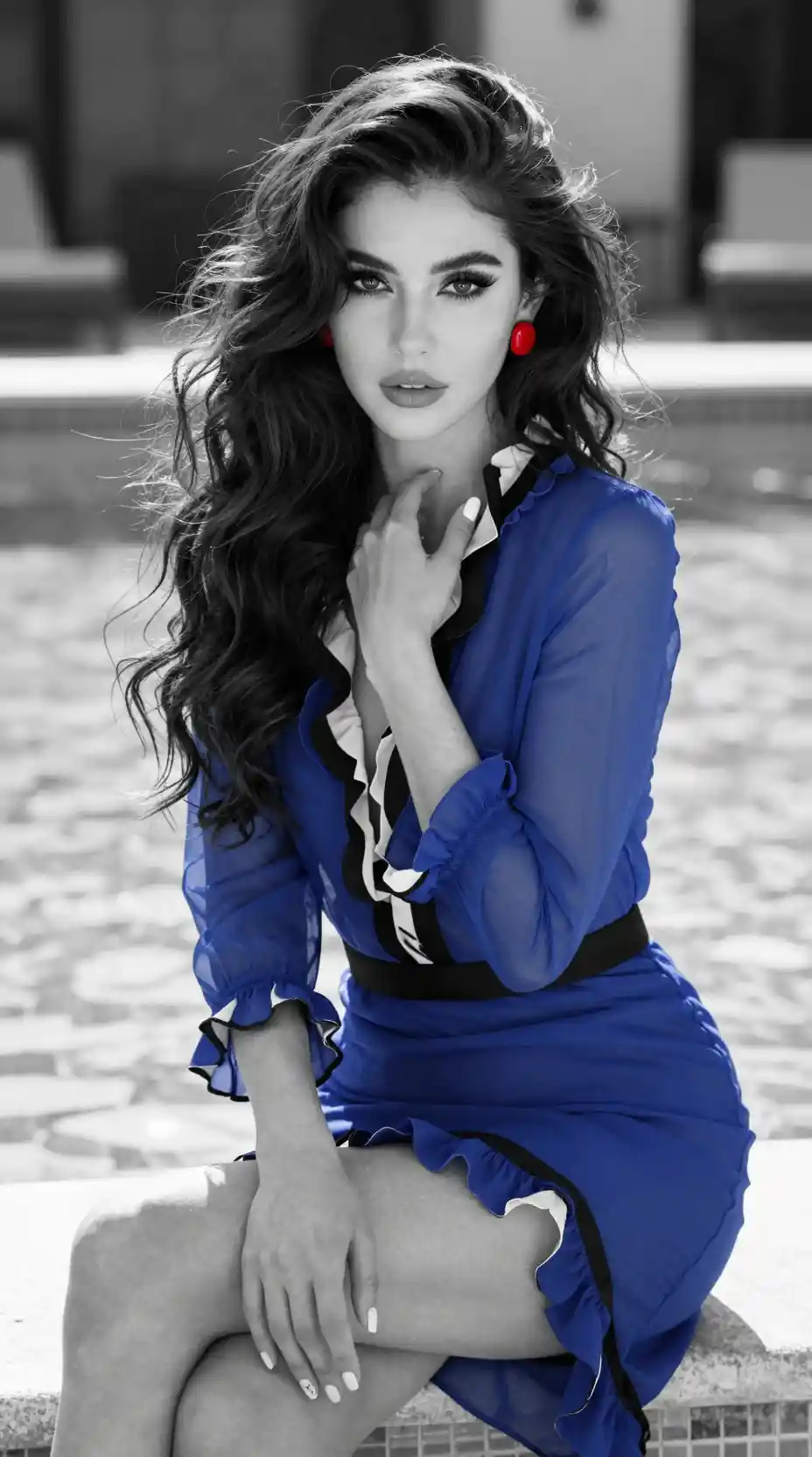 Elegant woman in blue dress by sunlit swimming pool