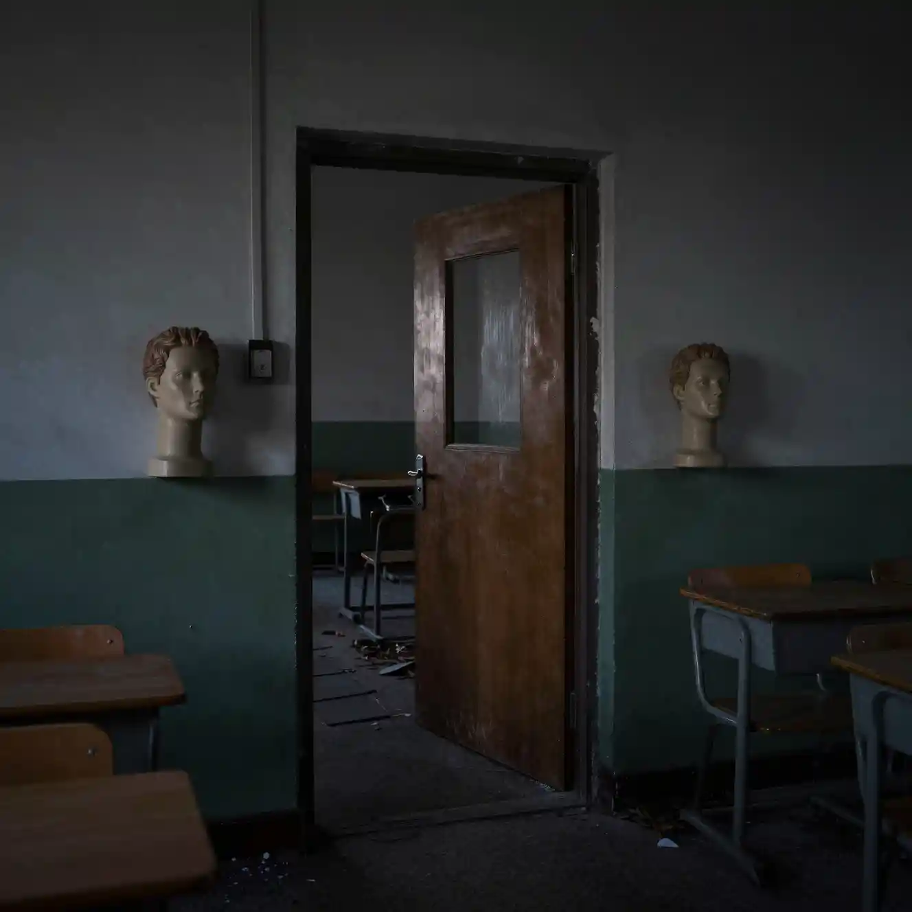 Abandoned classroom of mannequin heads staring toward a doorway