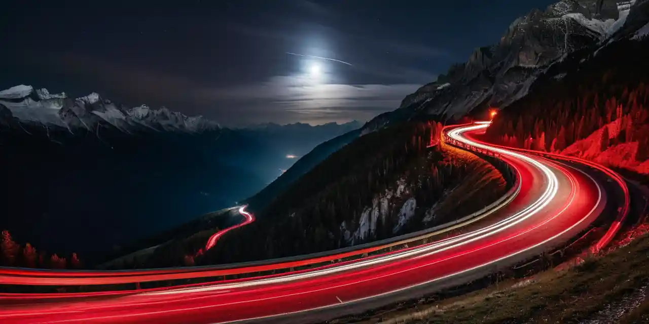 Winding mountain road at night with glowing light trails