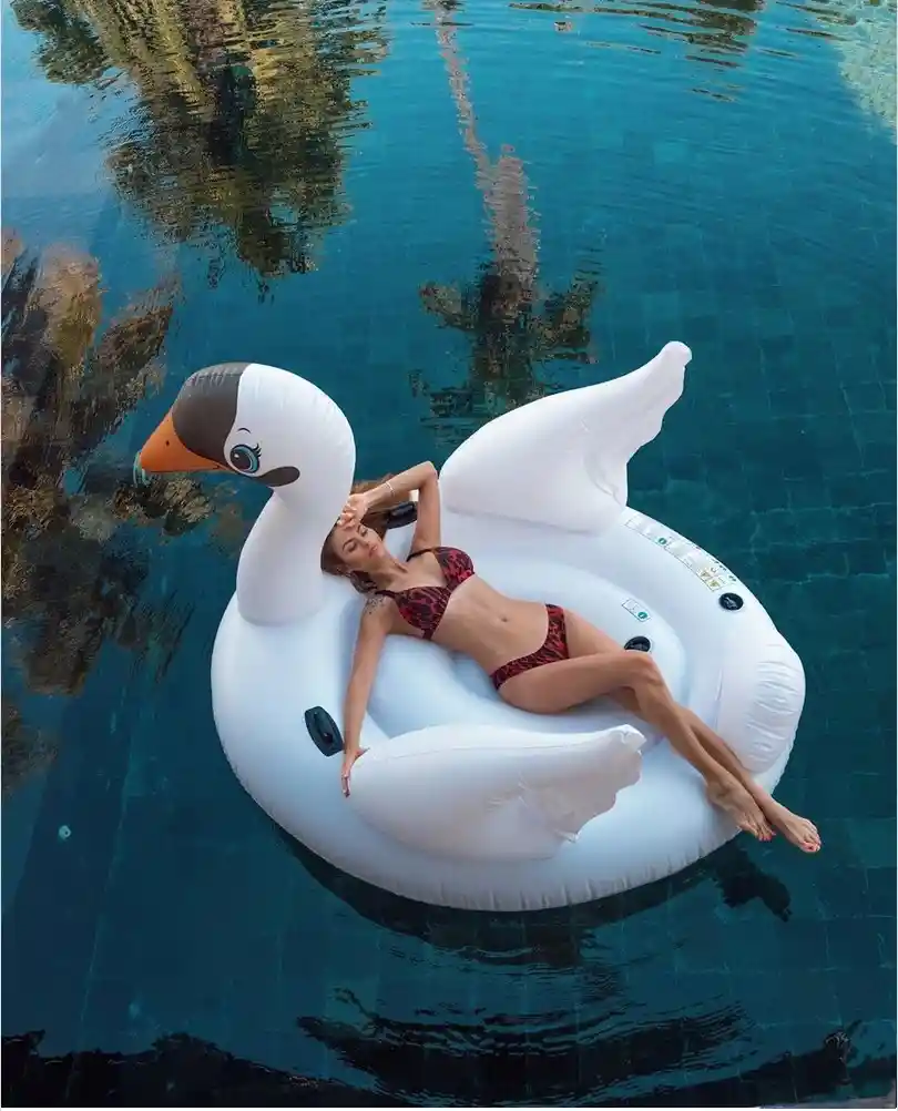 Woman lounging on swan float in blue pool