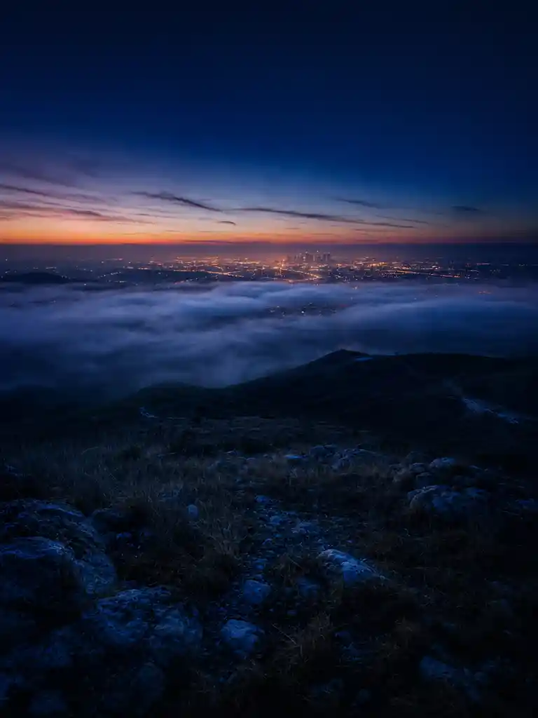 Foggy hilltop overlooking a distant glowing city skyline