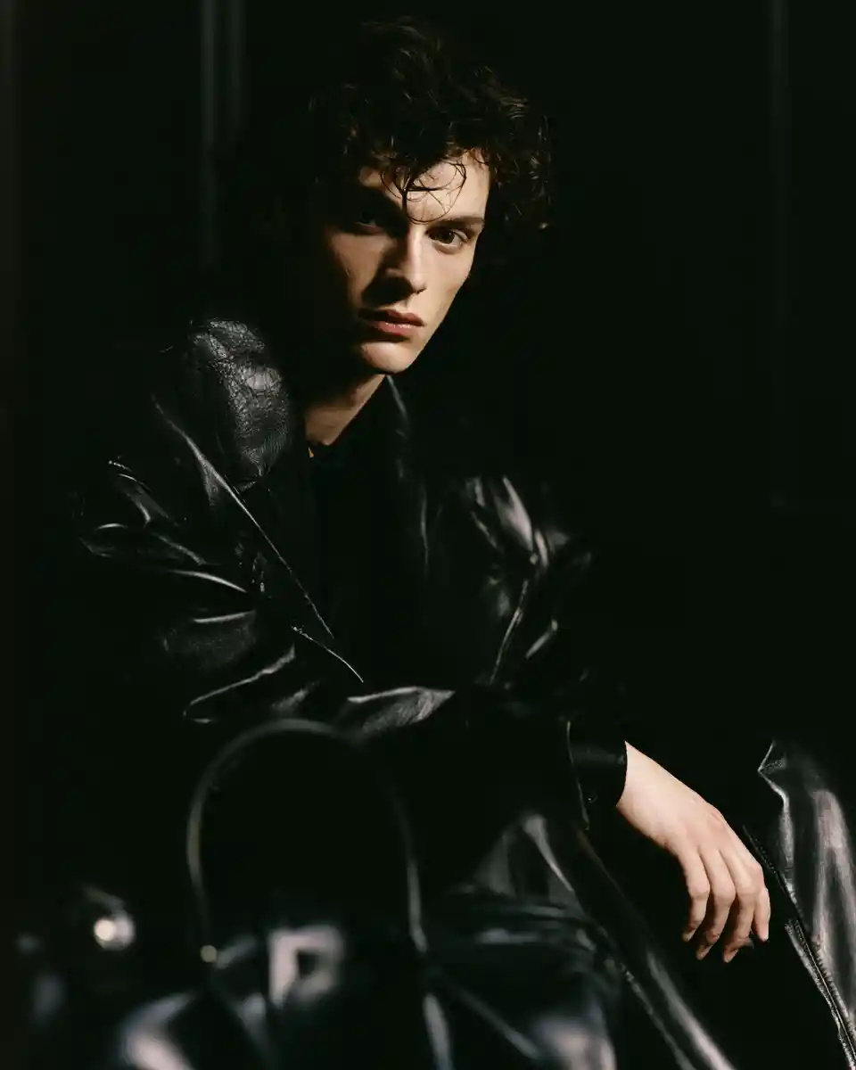 Confident fashion man seated with black leather outerwear