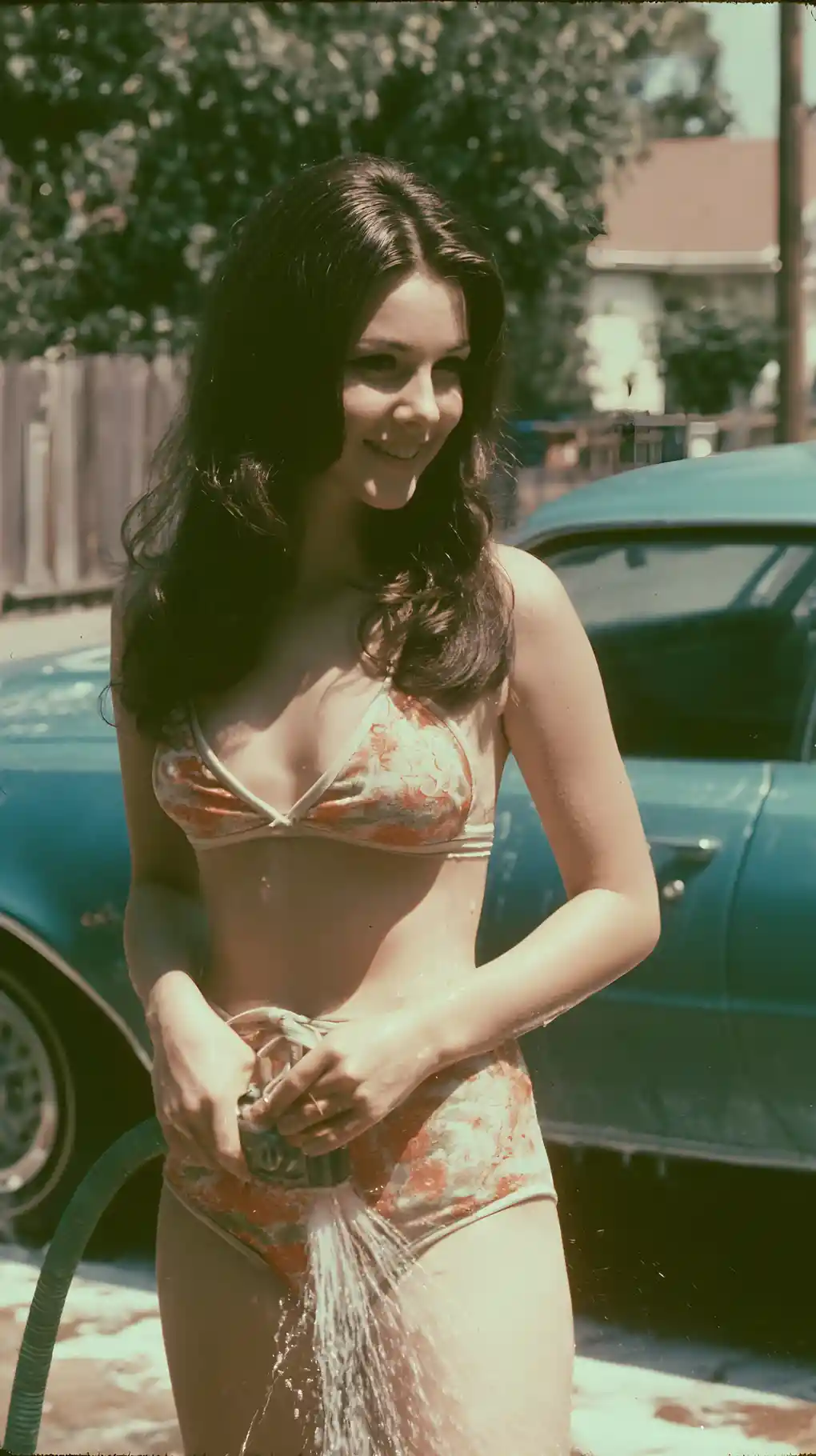Seventies young mother washing a car in suburban driveway