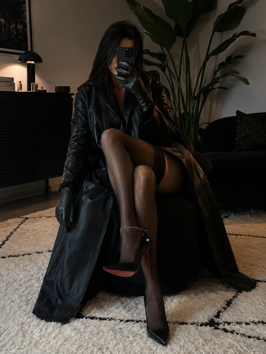 Seated woman in black coat and stockings on indoor chair