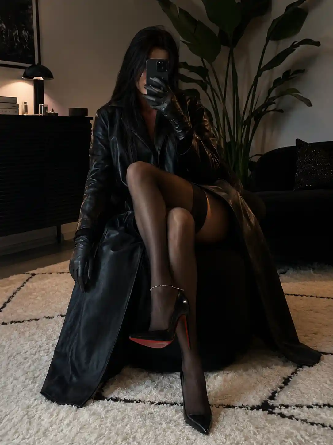 Seated woman in black coat and stockings on indoor chair