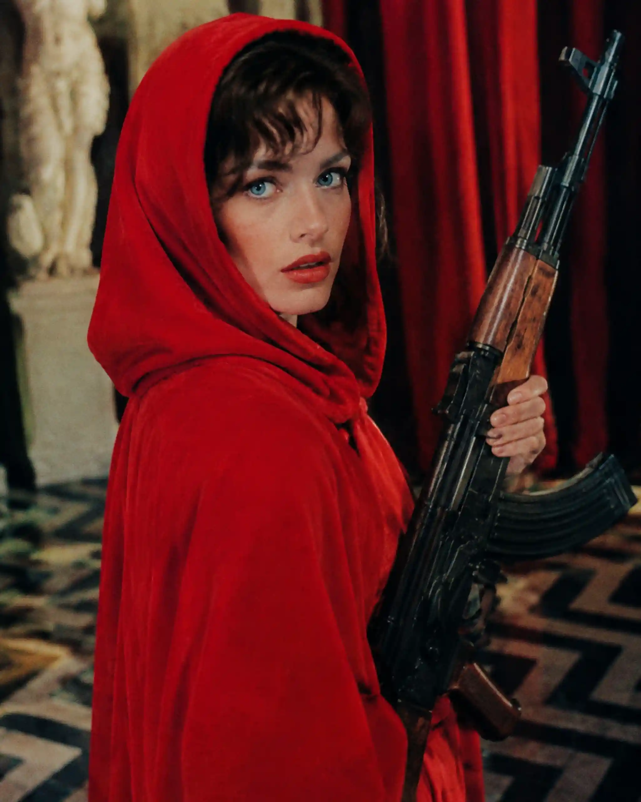 Woman in red hooded cape holding an AK47 rifle
