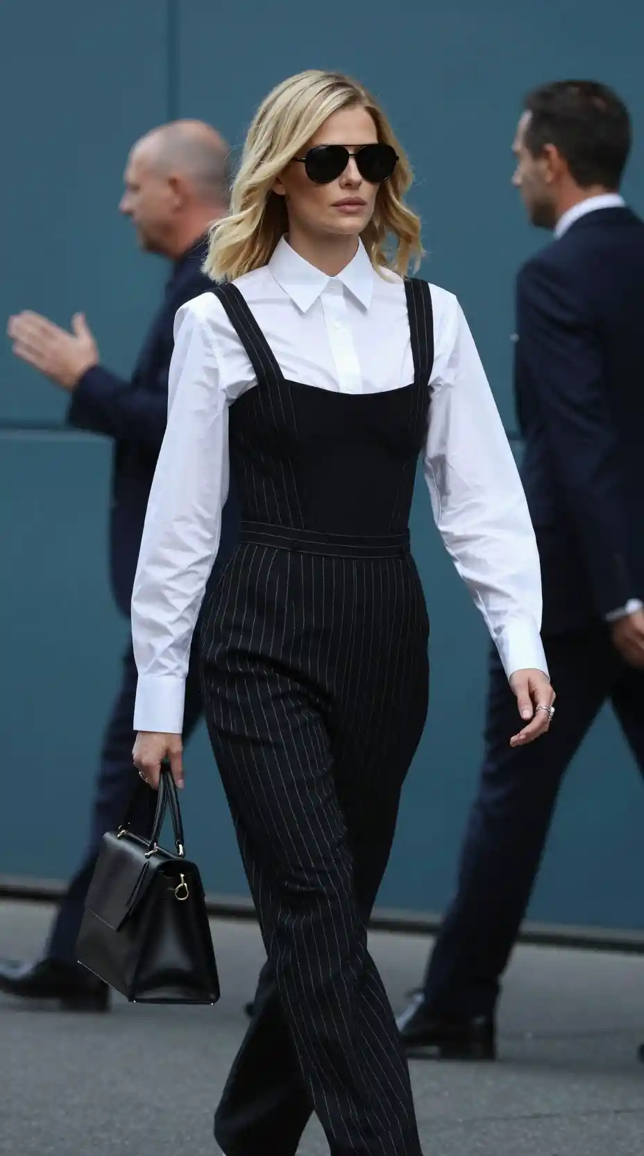 Confident blonde woman walking in striped city street style