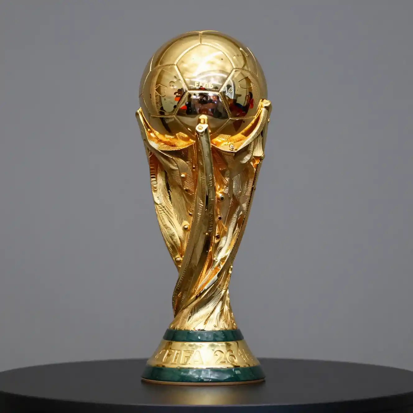 Golden World Cup style trophy on table with grey backdrop