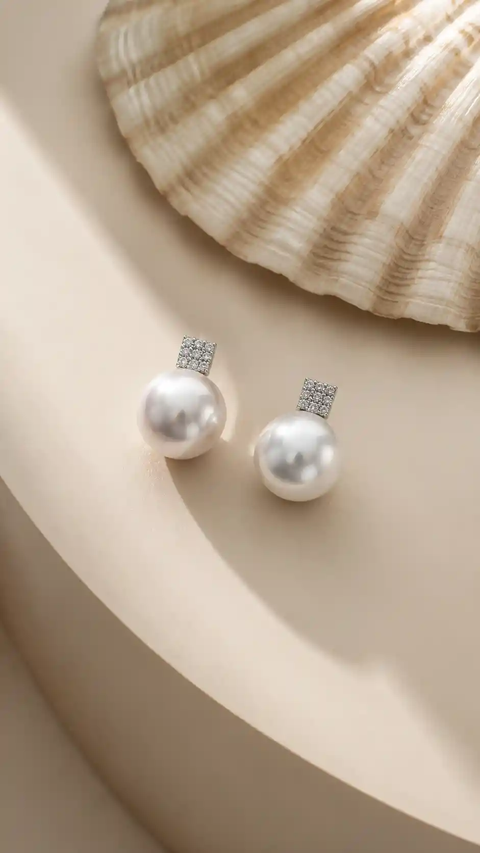 Minimalist close up earrings on shell inspired beige tabletop