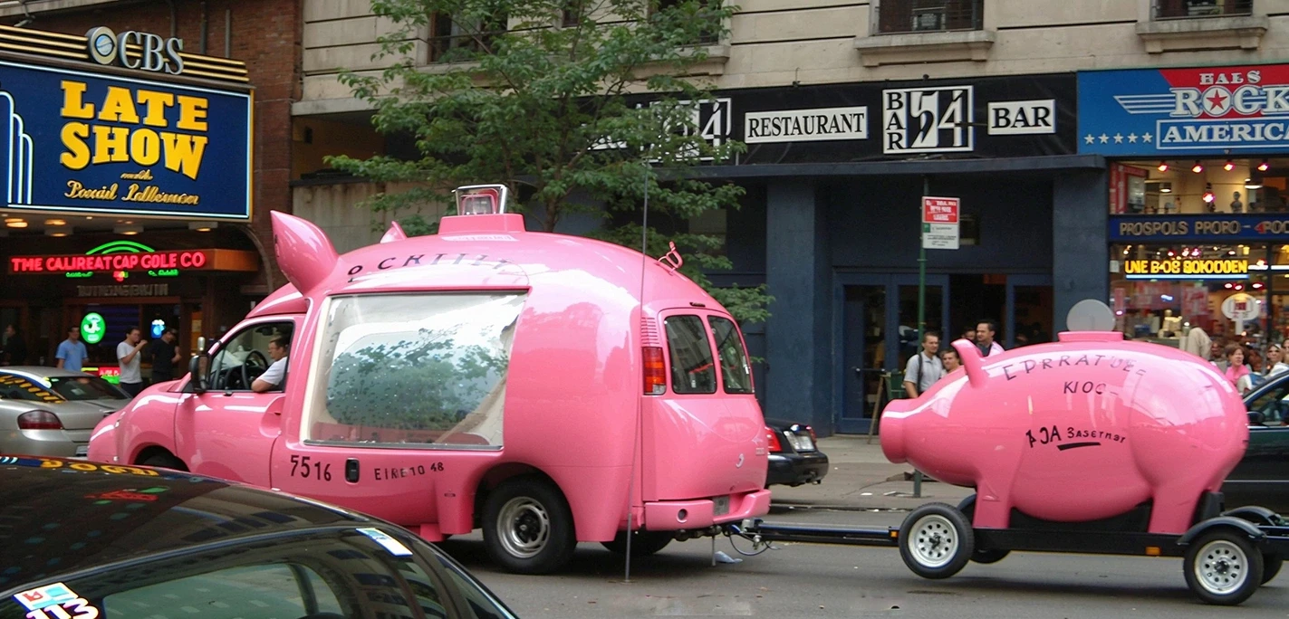 Pink pig van with matching trailer on busy city street