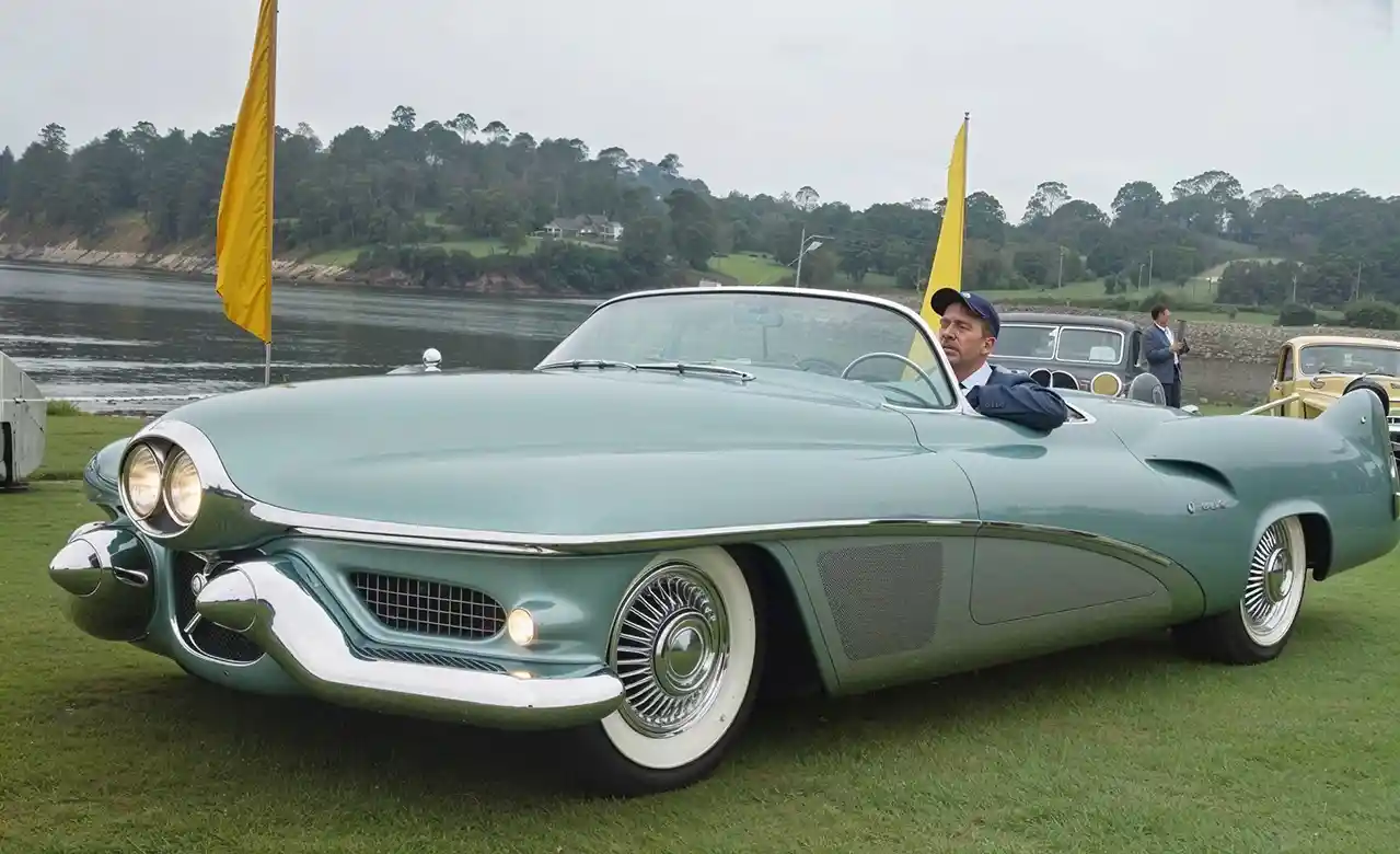 Vintage turquoise convertible parked by a calm lakeside