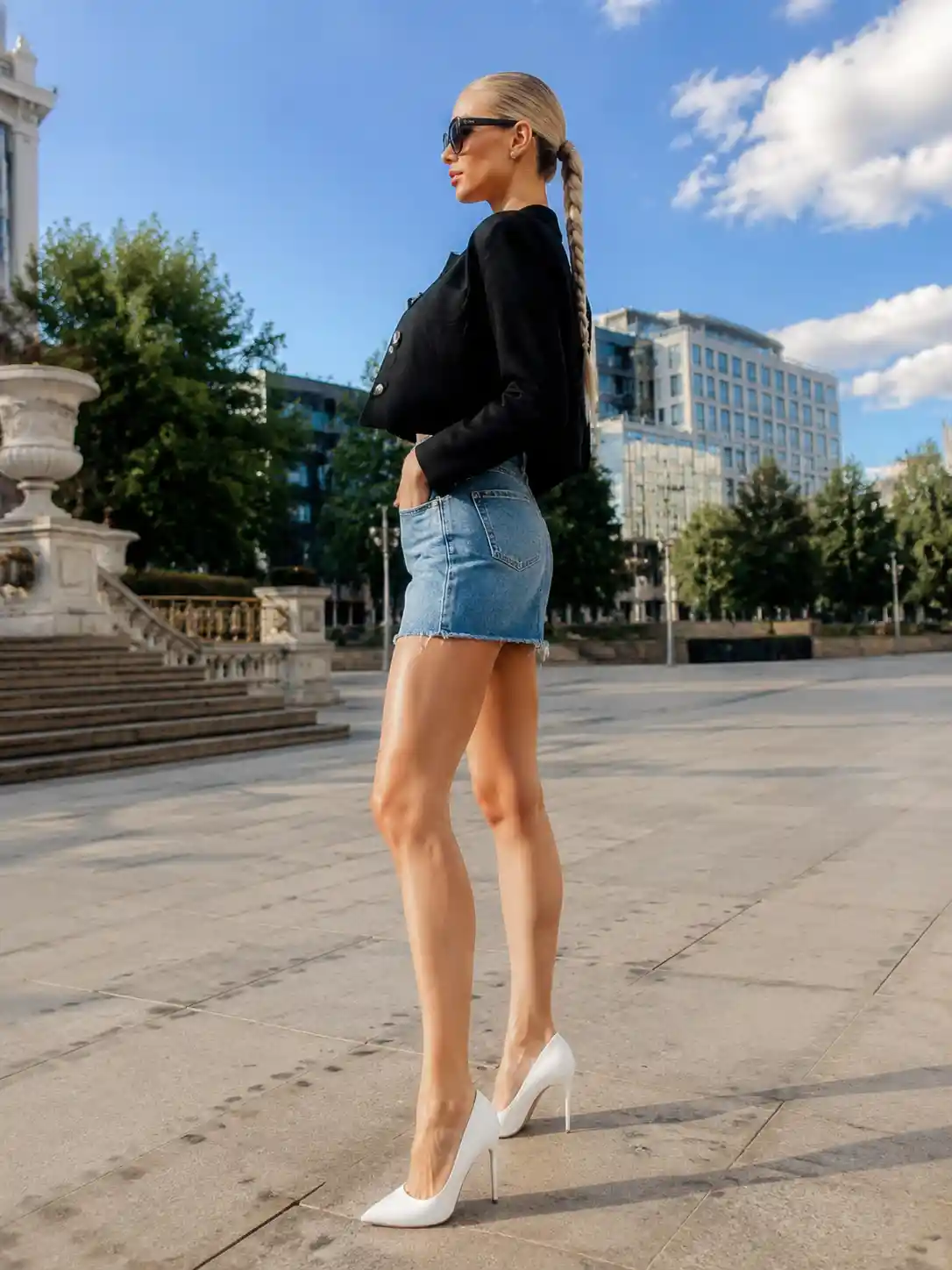 Tall blonde woman in denim skirt and white pumps