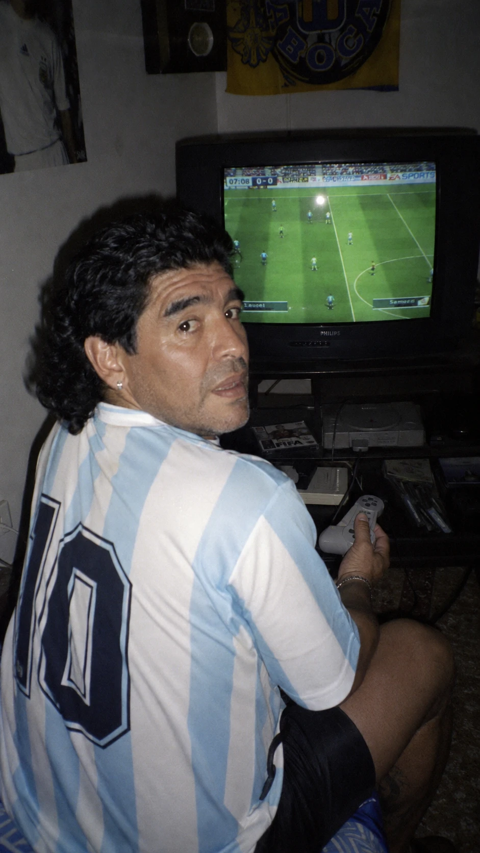 Man playing console game in dim 90s style bedroom