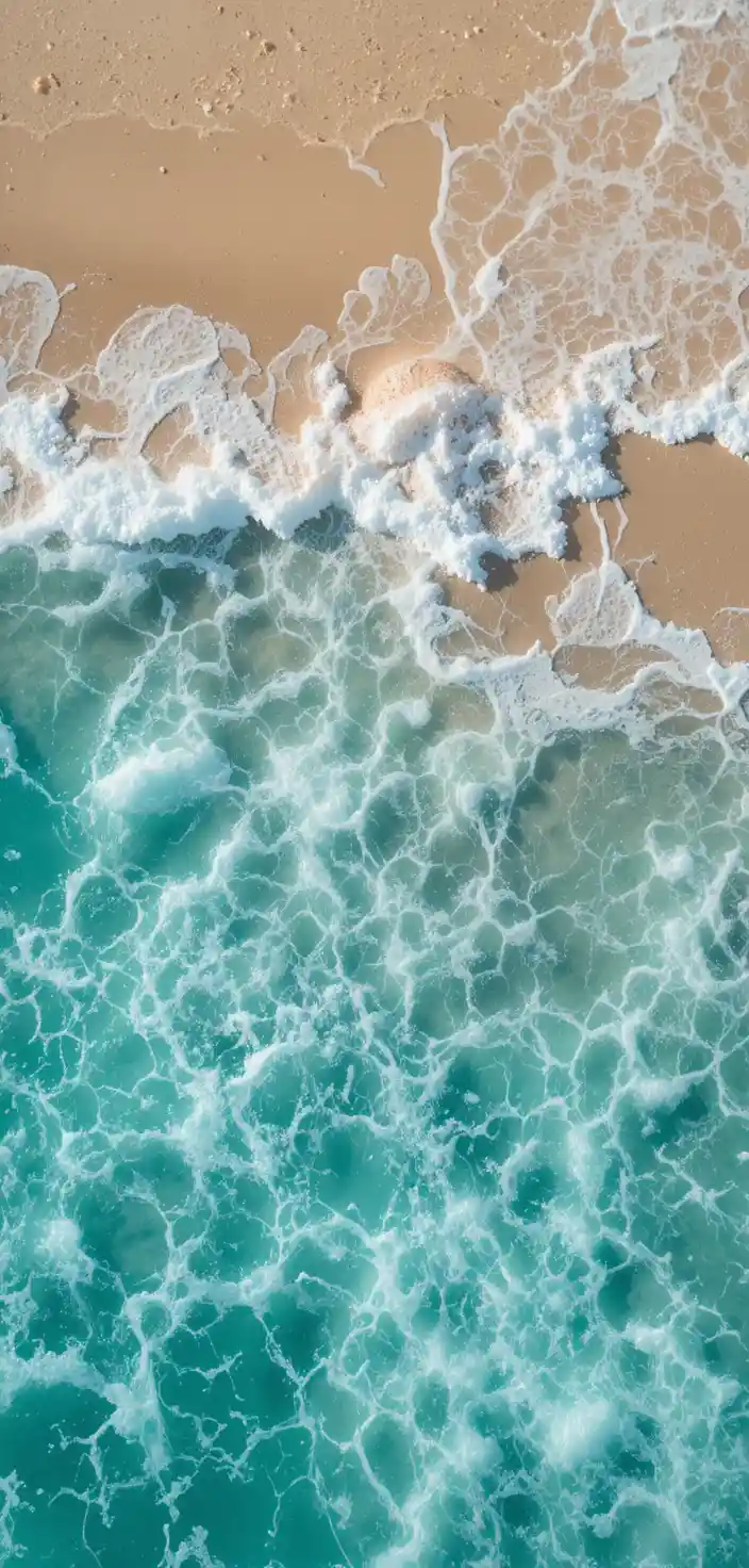 Peaceful turquoise waves washing over clean golden sand