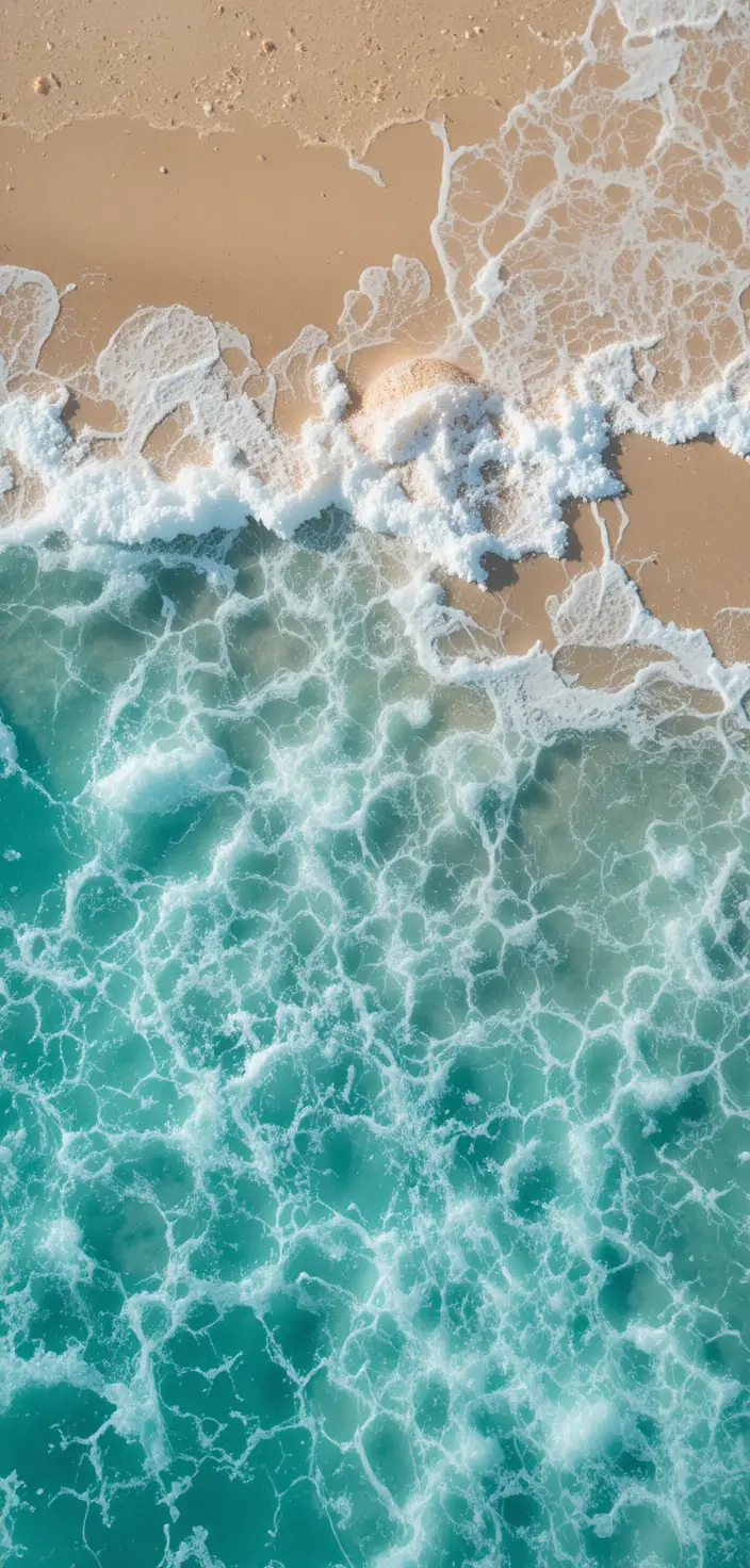 Peaceful turquoise waves washing over clean golden sand