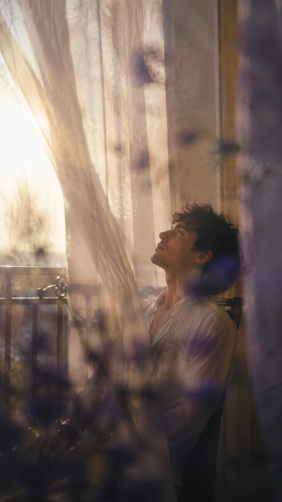 Serene young man gazing upward on a sunny balcony