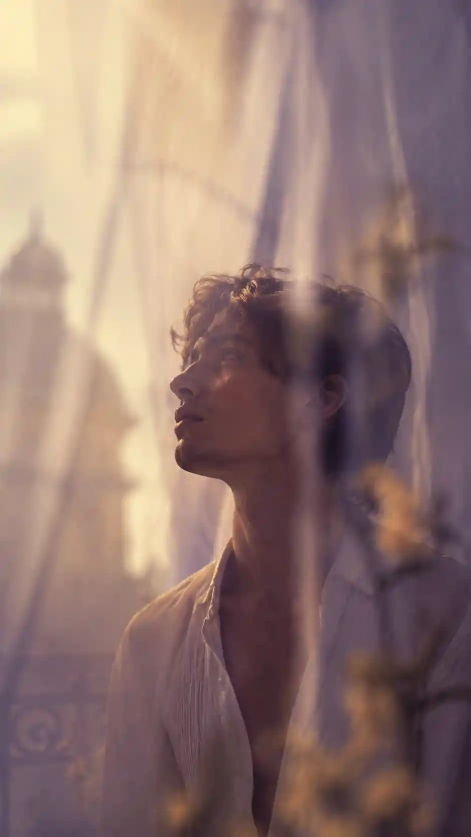 Serene young man gazing upward on a sunlit balcony