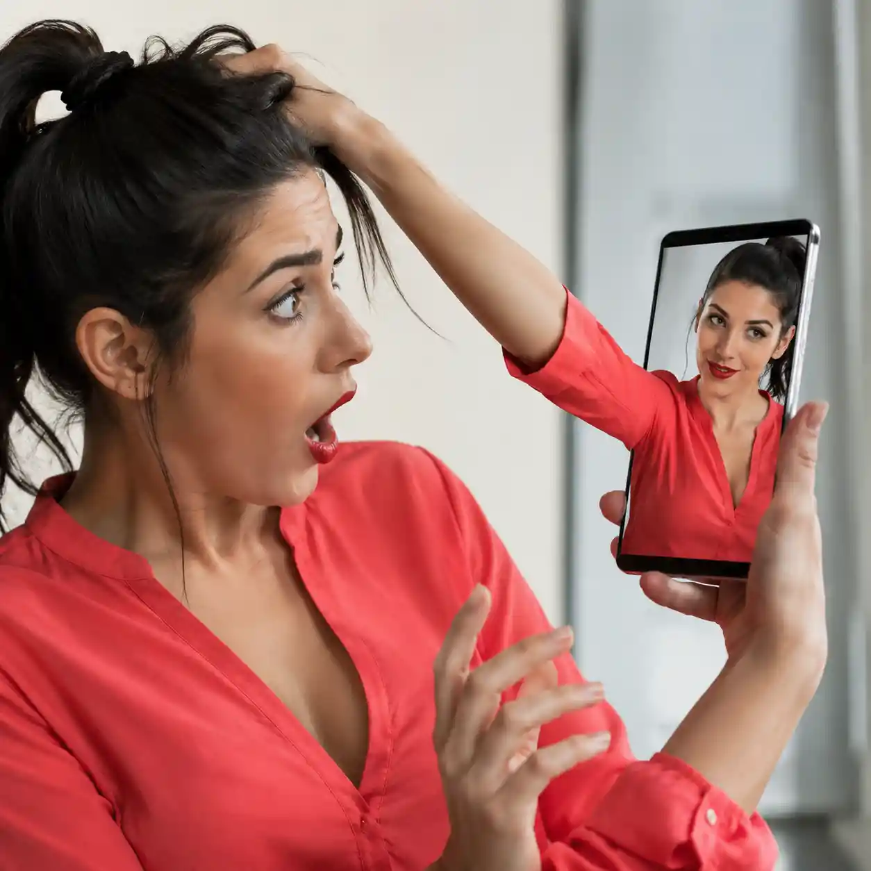 Woman staring at her phone as her reflection grabs her hair