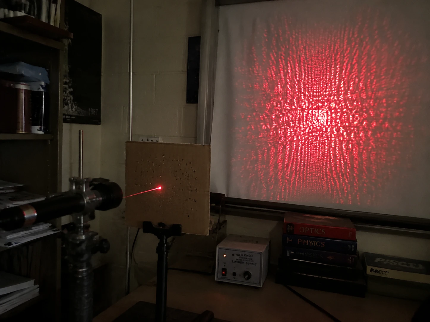 Makeshift physics lab bench with red laser interference pattern