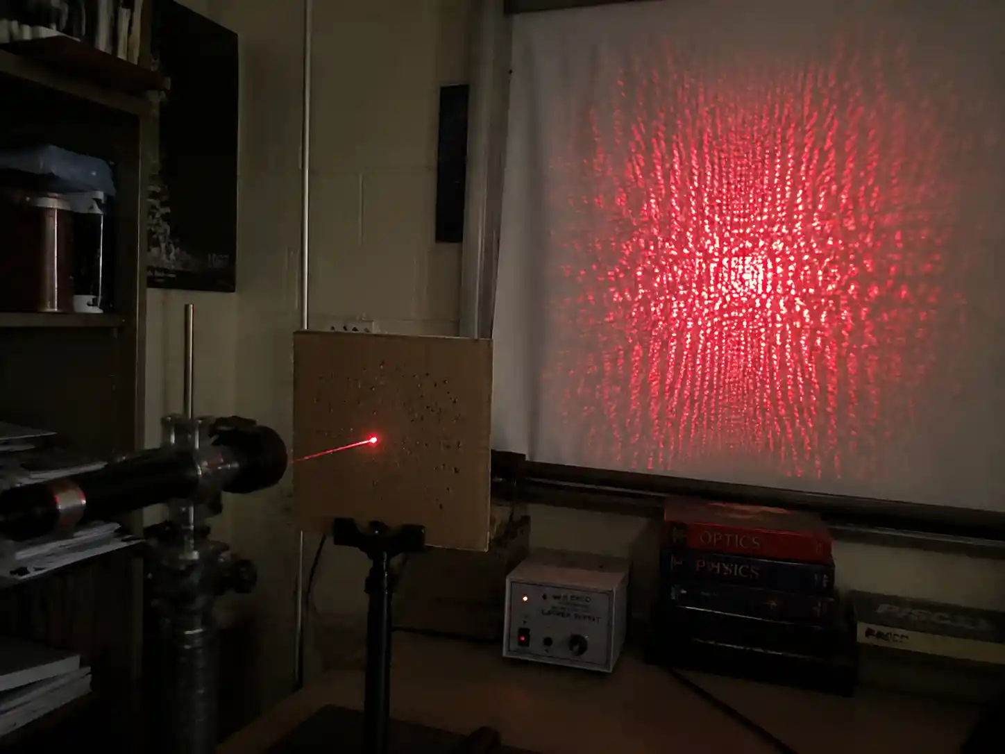 Makeshift physics lab bench with red laser interference pattern