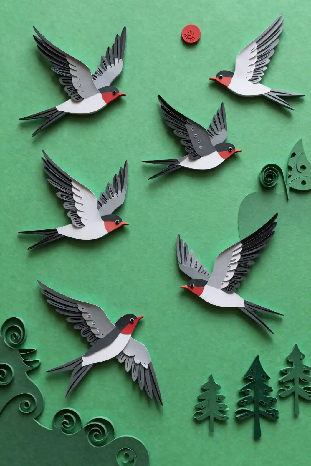 Paper swallows in dynamic flight against green abstract forest