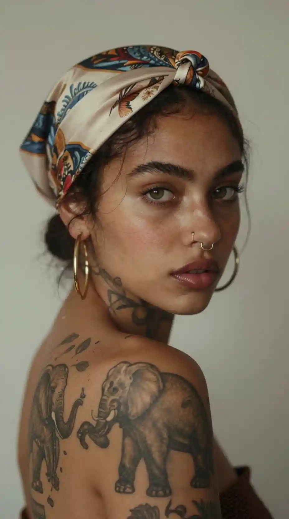 Moody portrait of a tattooed woman in silk headscarf