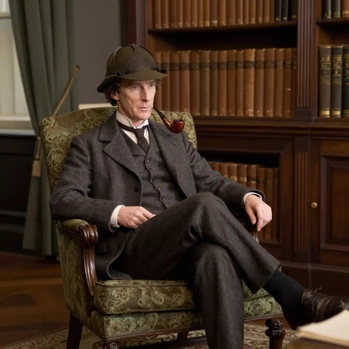 Man with pipe seated in a victorian library armchair