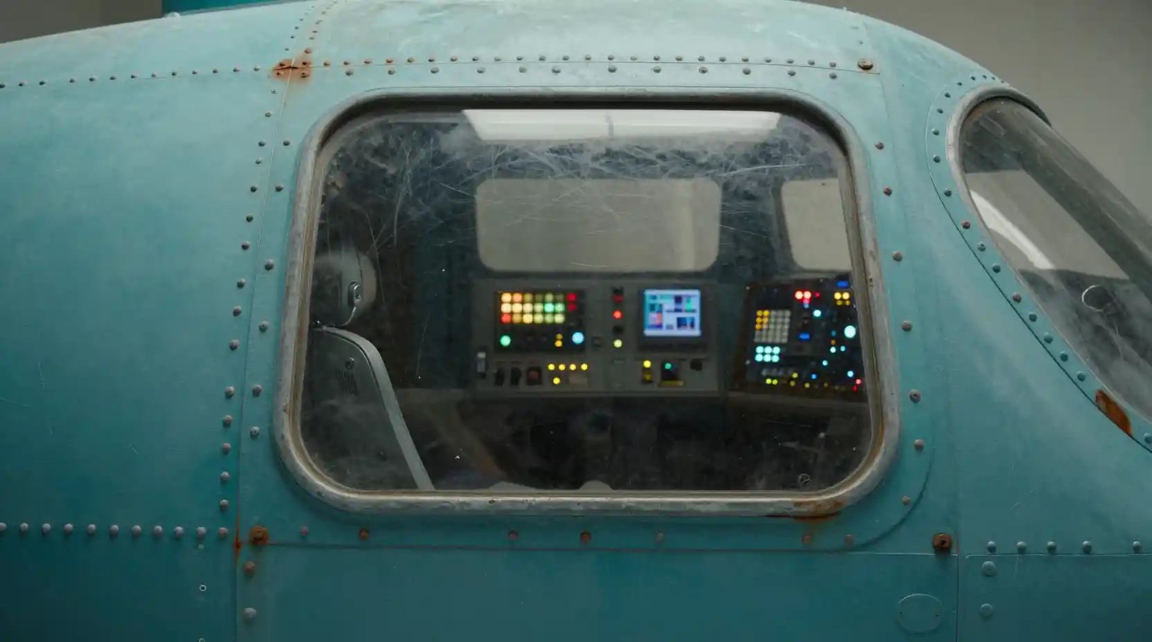 Close up cockpit window of a weathered teal spaceship