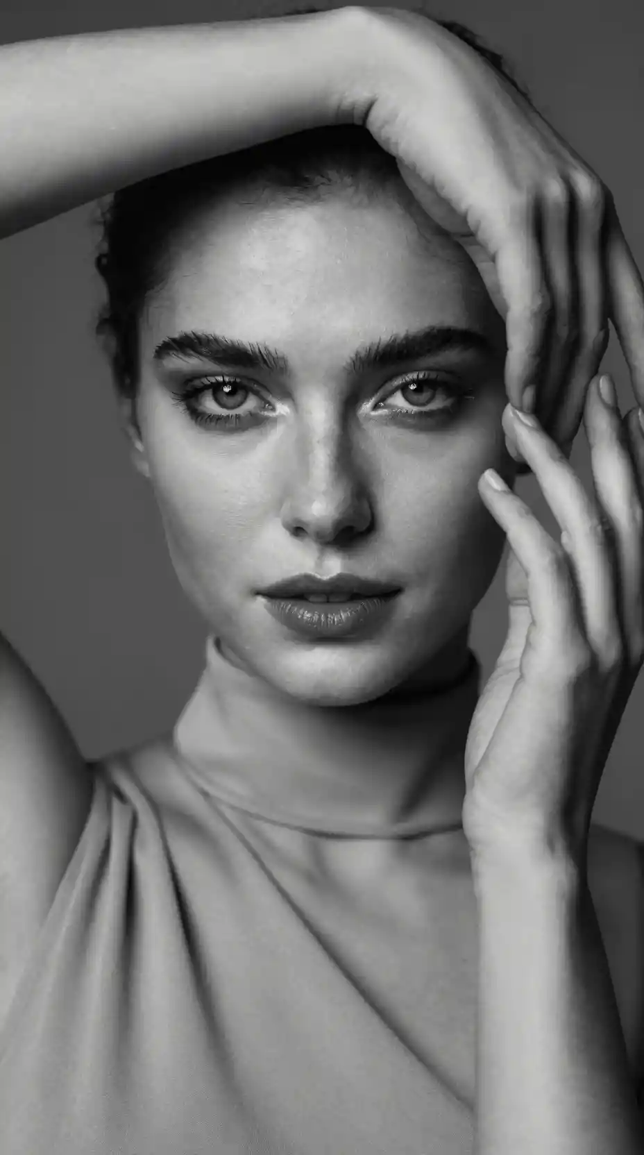 Intense grayscale portrait of a woman framed by her hands
