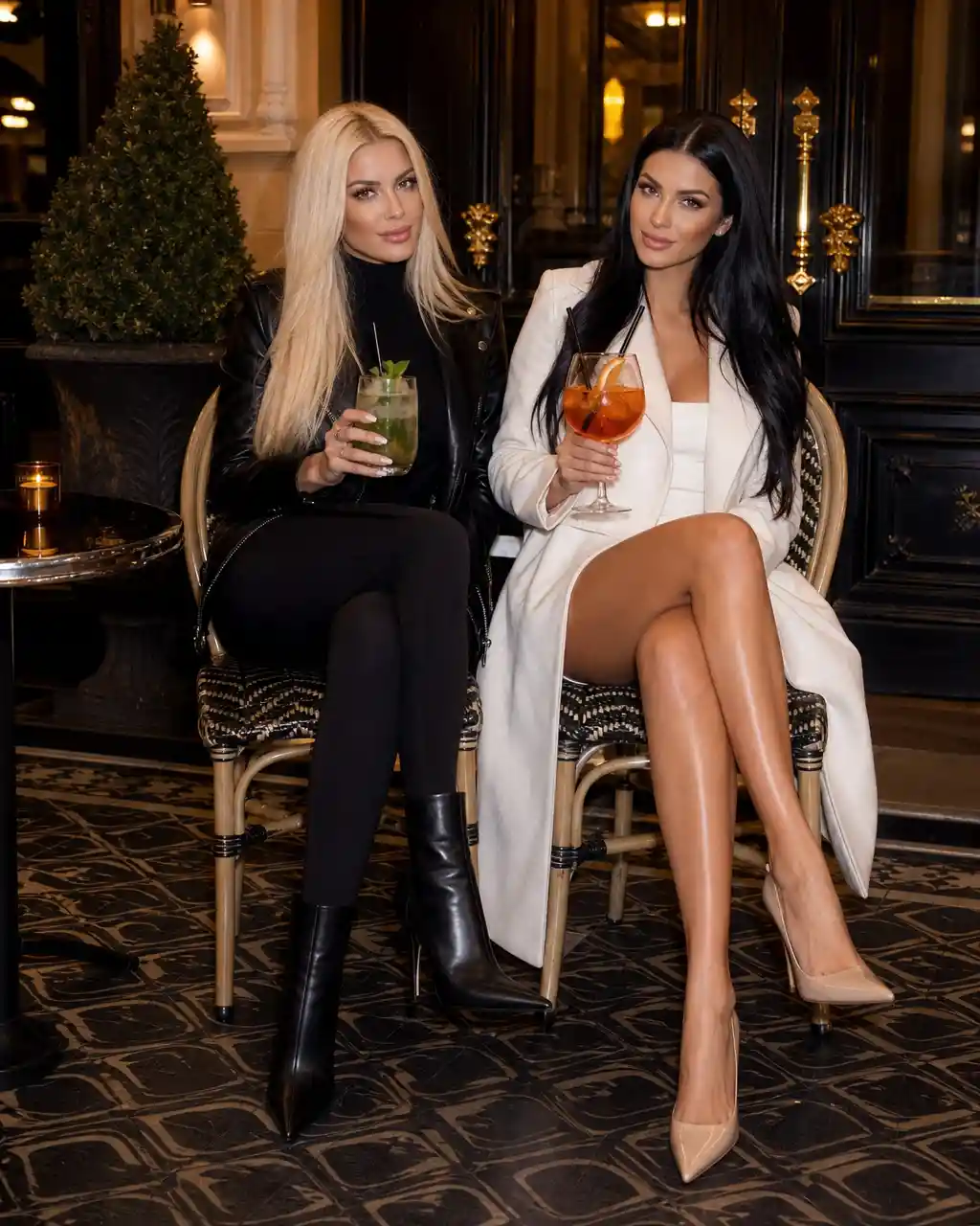 Two stylish women seated outside an elegant building entrance