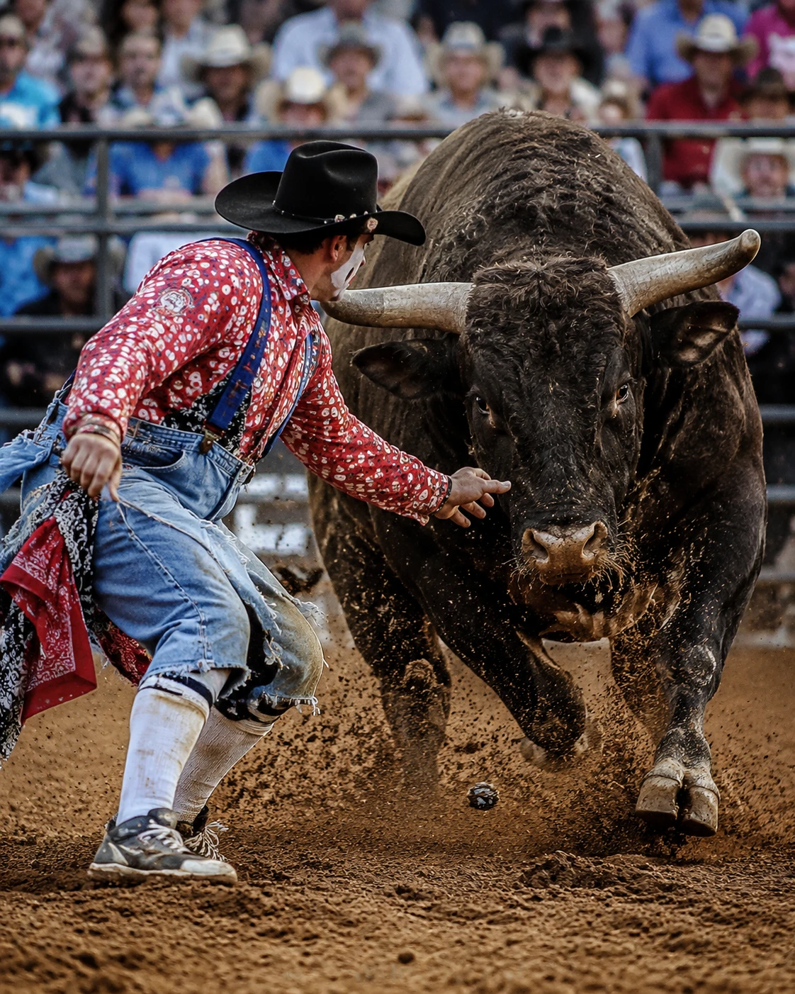 Payaso de rodeo enfrentando a un toro embistiendo en la arena